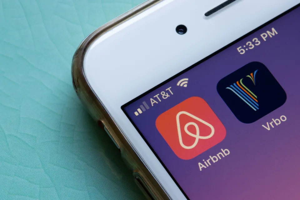 Close-up of mobile phone with Airbnb and VRBO app icons.